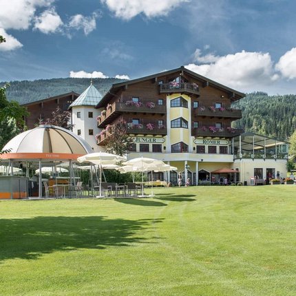 Hotel by golf course with green lawn and forested hills in the background