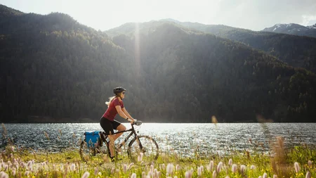Drei Länder, du und dein Rad: Den Reschensee grenzüberschreitend entdecken © IDM Südtirol - Alex Moling Frau fährt Fahrrad am Seeufer mit Bergen im Hintergrund