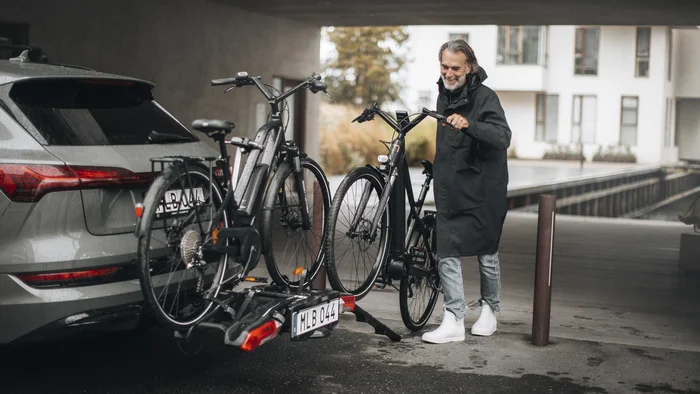 Der Thule Epos © Thule Mann befestigt ein Fahrrad auf dem Heckträger eines grauen Autos