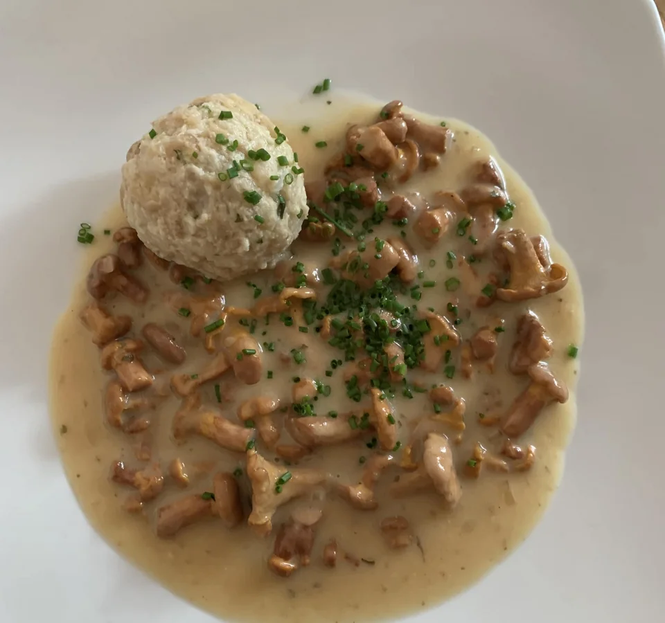 Broodknödel met romige cantharellen en bieslook op wit bord
