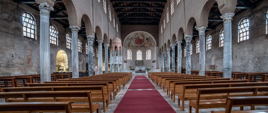 Interieur van een kerk met houten banken en een rood tapijt gangpad