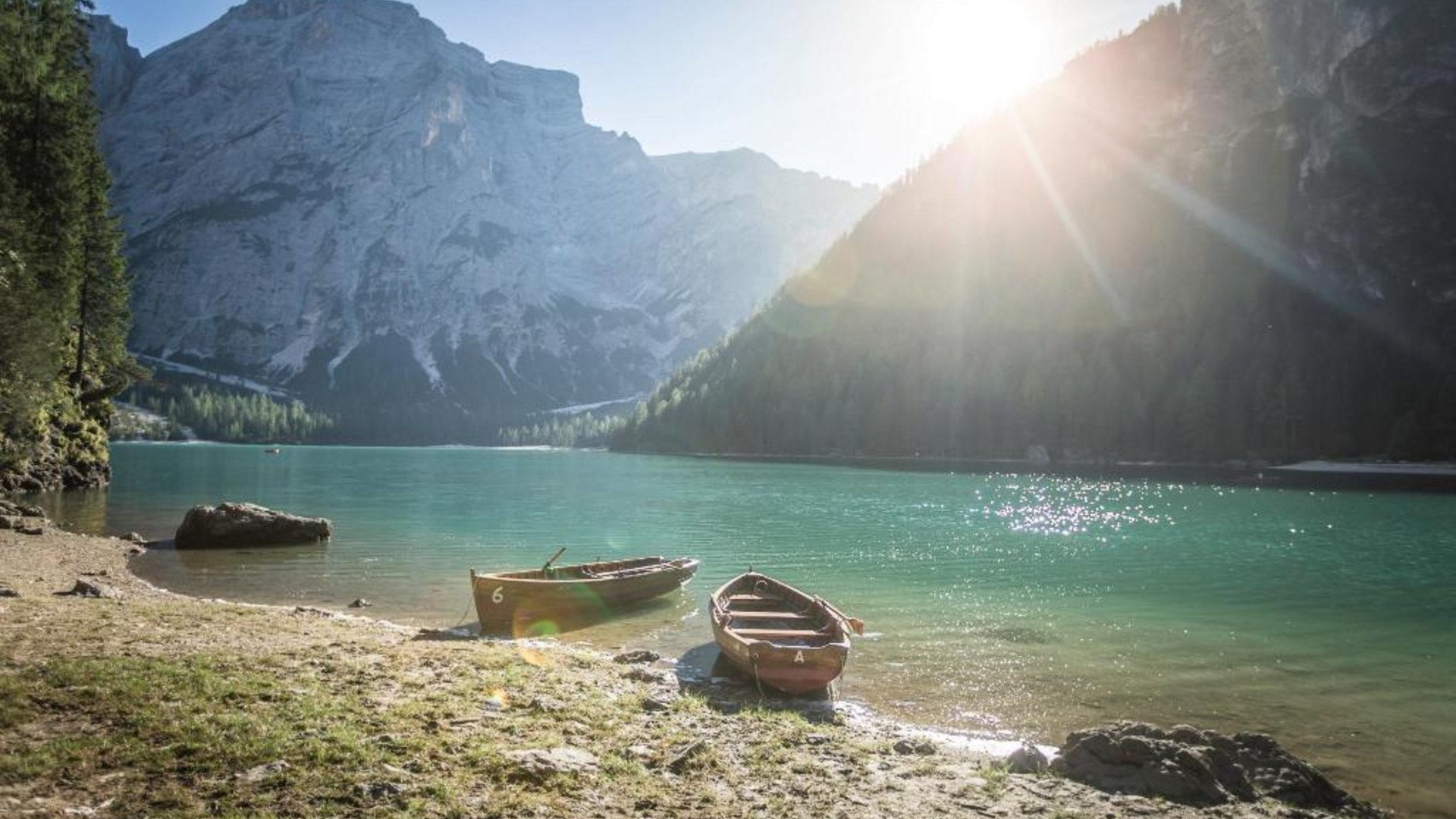 Two boats on the shore of a mountain lake with sunlight