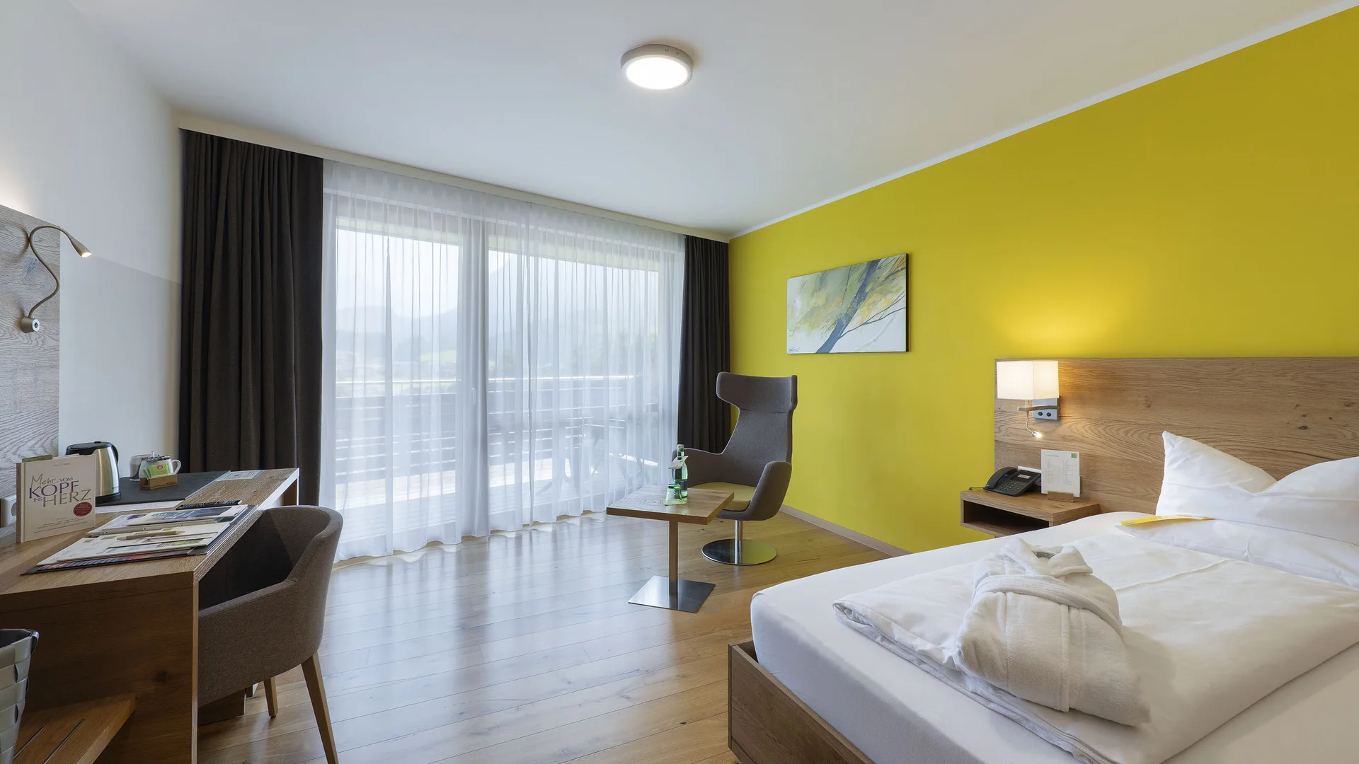 Modernes Hotelzimmer mit gelber Wand und Balkon mit Vorhängen