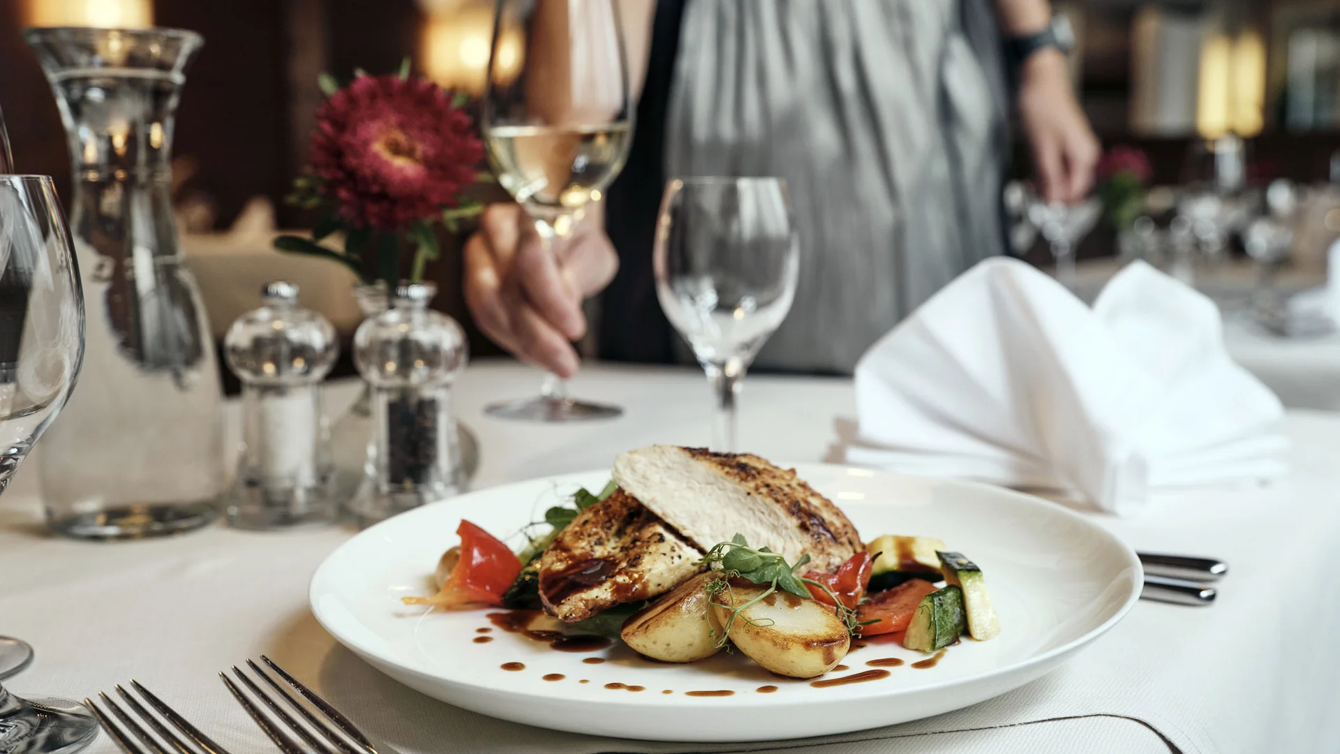 Hotel Andreas Hofer Kufstein **** © Dominik Hollaus Gegrilltes Hähnchen mit Gemüse und Kartoffeln auf weißem Teller im Restaurant