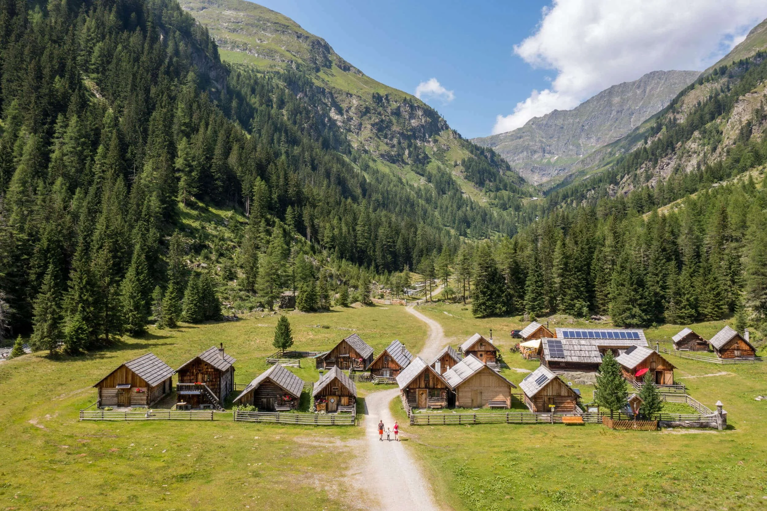 Kleine Holzhütten in einem grünen Tal mit Bergen und Kiefernwäldern