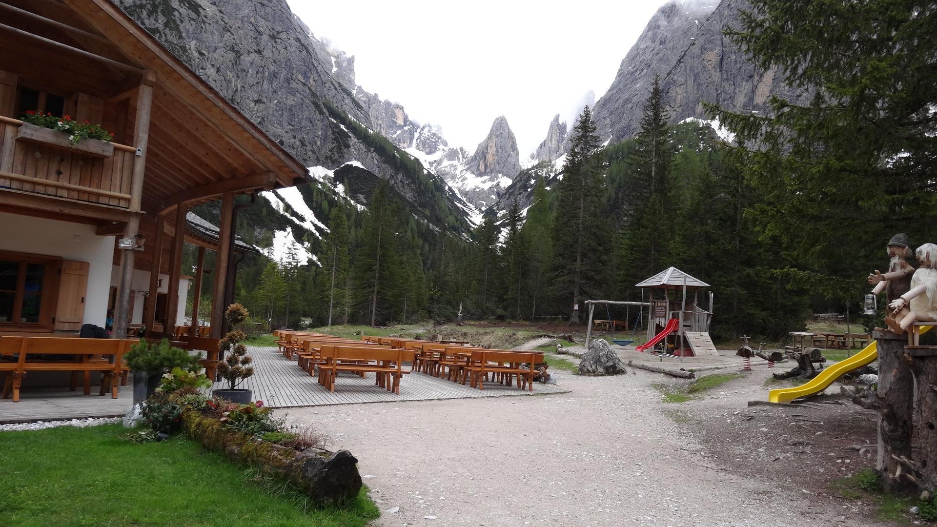 Wood terrace with benches by a mountain house in the Alps with snow and playground