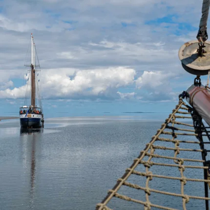 Zeilboot op kalm water onder bewolkte hemel