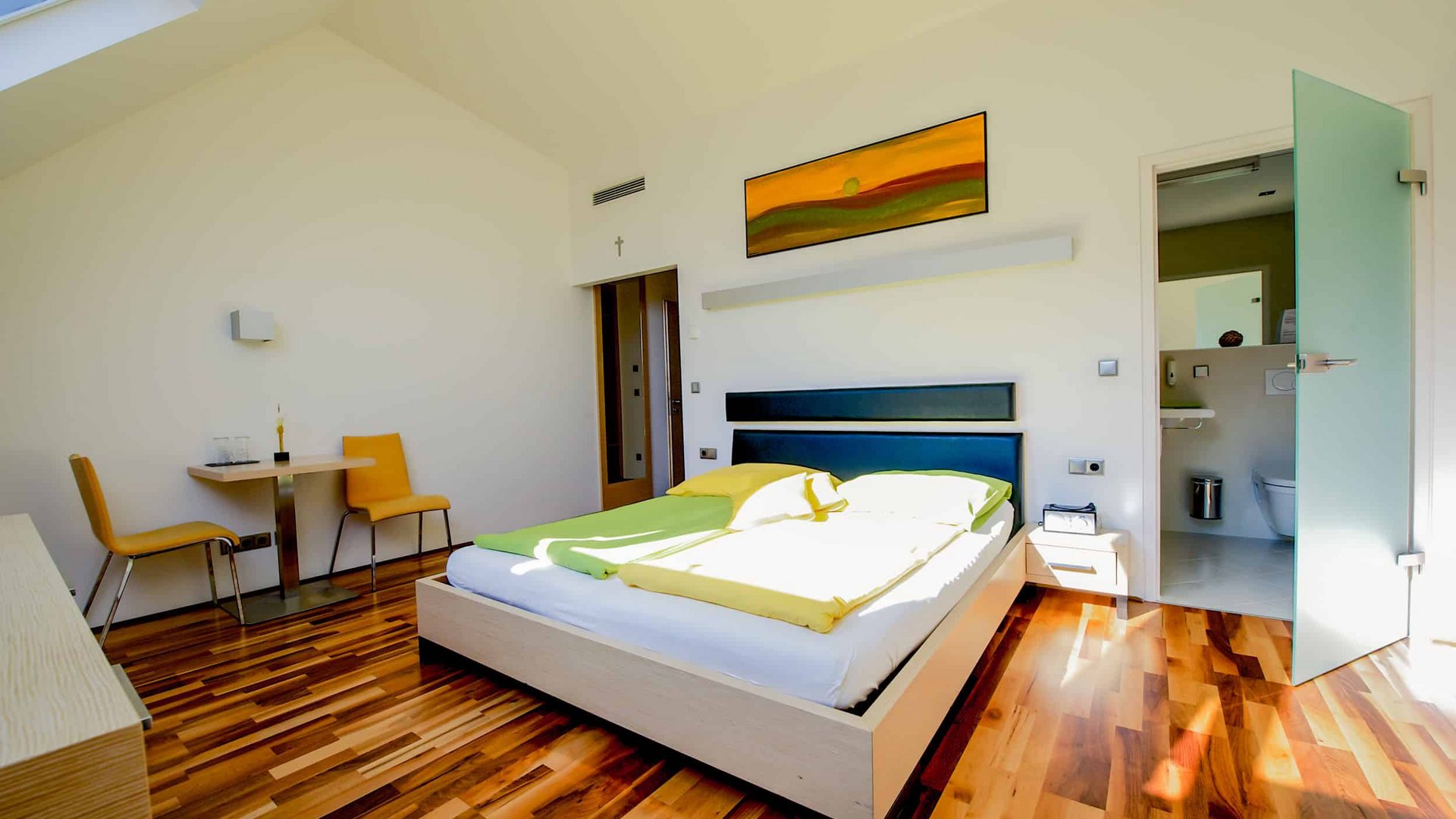 Modern bedroom with wooden floor, double bed and en-suite bathroom