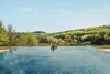 Collective enquiries © Falkensteiner Hotels & Residences Person relaxing in infinity pool overlooking wooded hills