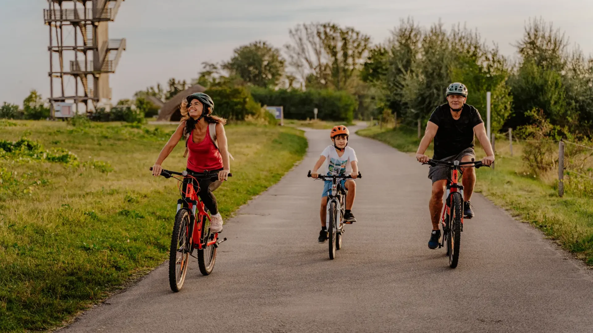 Familie mit Kind fährt Fahrrad auf einem Landweg bei sonnigem Wetter
