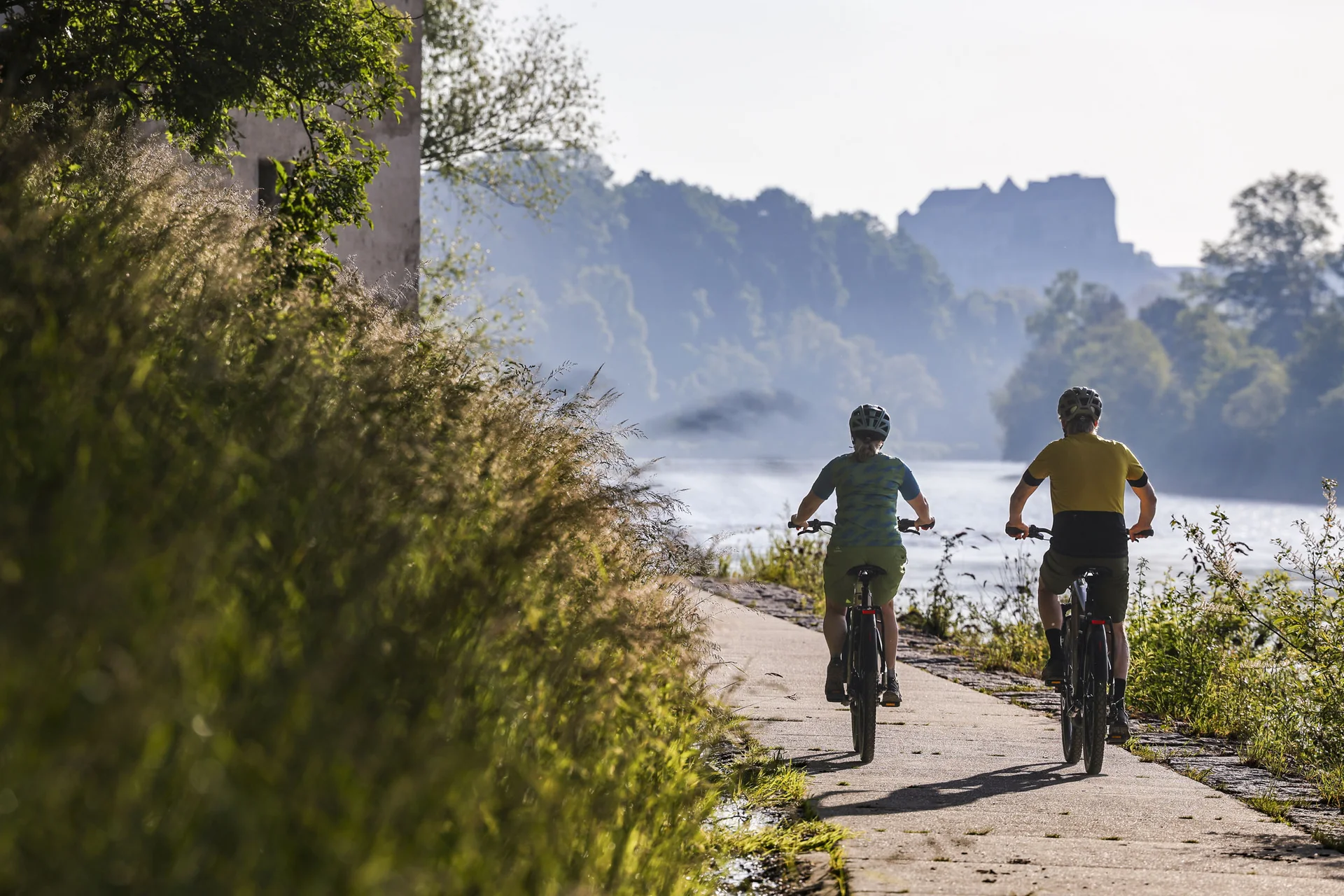 Zwei Radfahrer auf einem Flussweg bei sonnigem Wetter