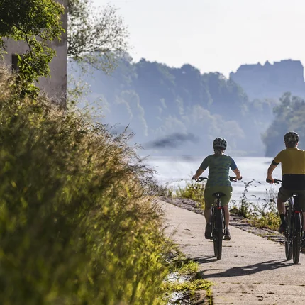 Zwei Radfahrer auf einem Flussweg bei sonnigem Wetter