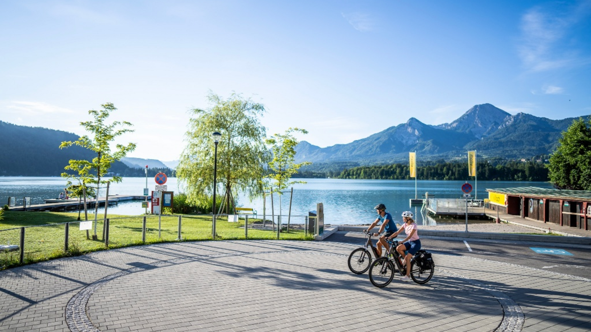 Two cyclists by the lake with mountains in the background