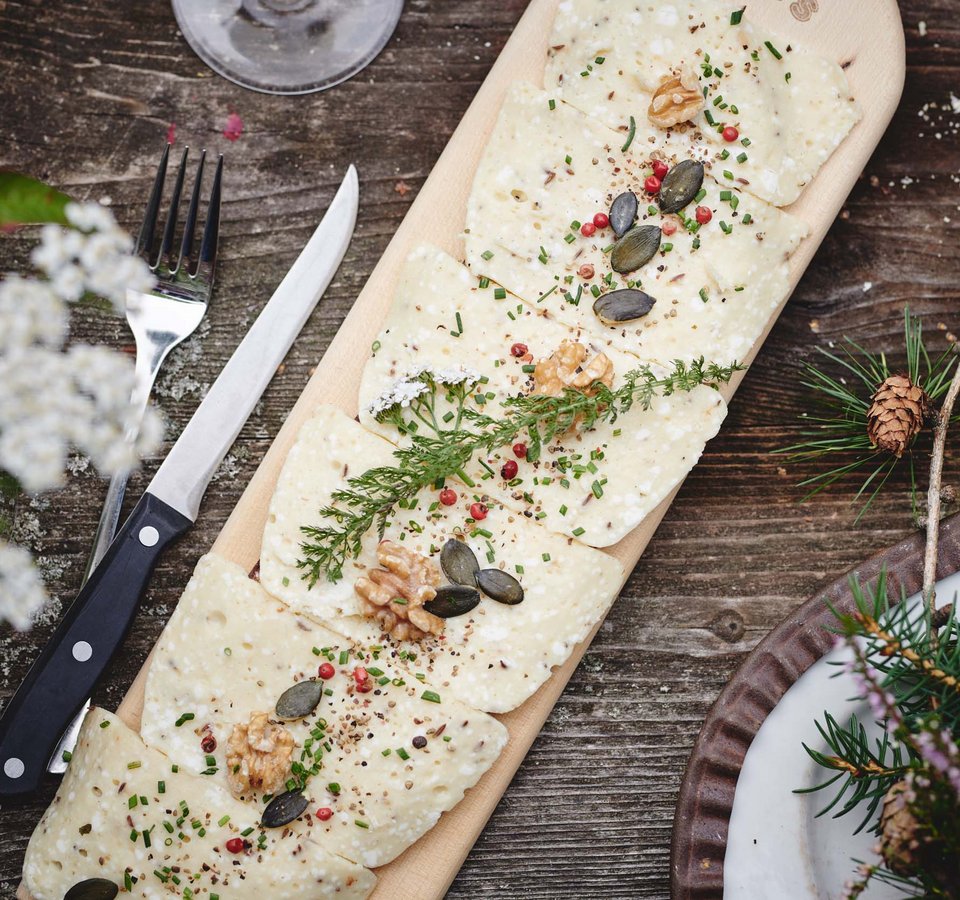 Cheese with herbs, nuts, and seeds served on a wooden board