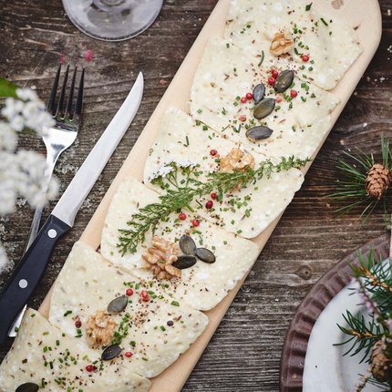 Cheese with herbs, nuts, and seeds served on a wooden board