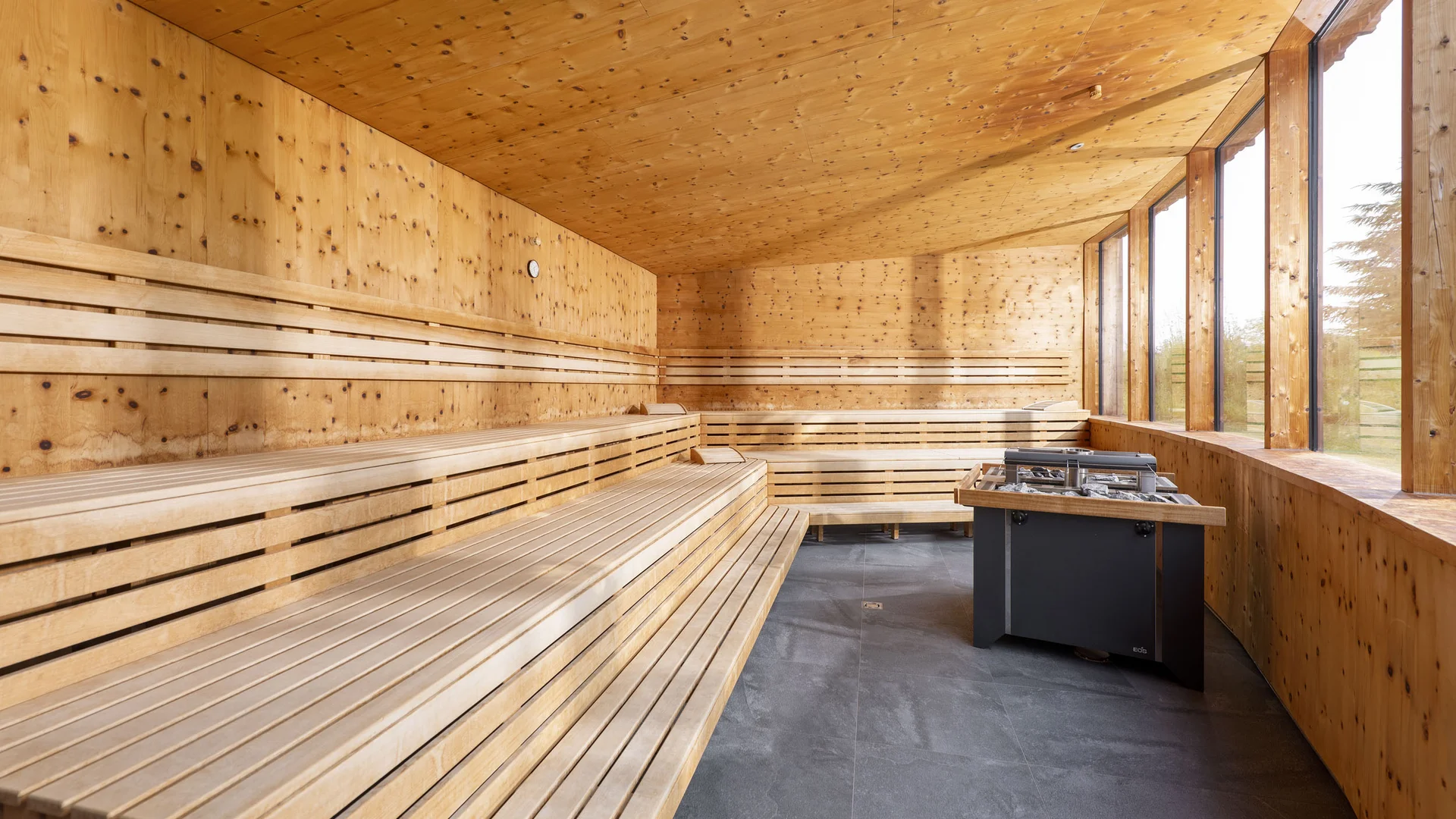 Moderner Sauna-Innenraum mit Holzbanksitzplätzen und großen Fenstern