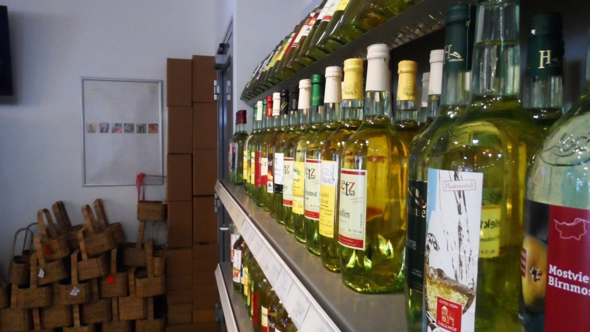 Most-Radroute Regal mit vielen verschiedenen Weinflaschen und Körben in einem Laden