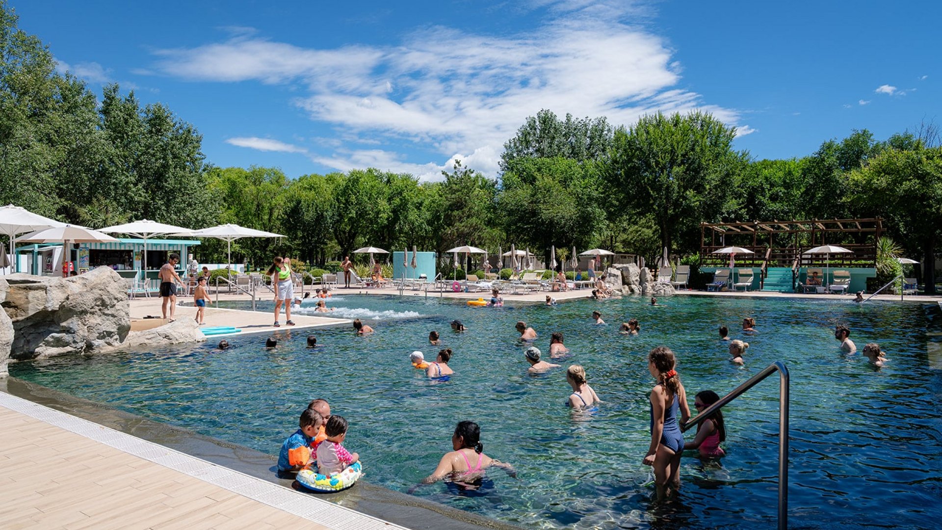 People swimming and relaxing in an outdoor pool on a sunny day