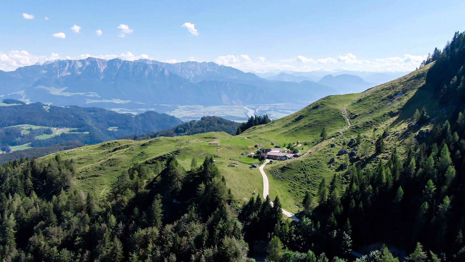 Mountain landscape with green valley, cabins, and mountains in the background