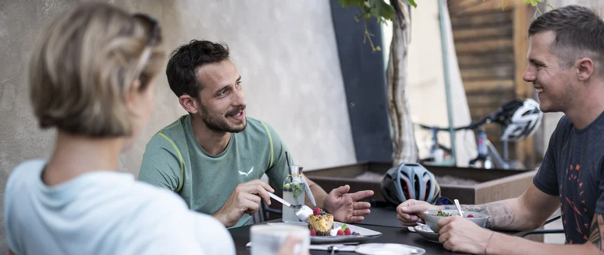Kulinarisch unterwegs in Tramin © IDM Südtirol - Alex Filz Drei Personen unterhalten sich beim Essen und Trinken im Freien