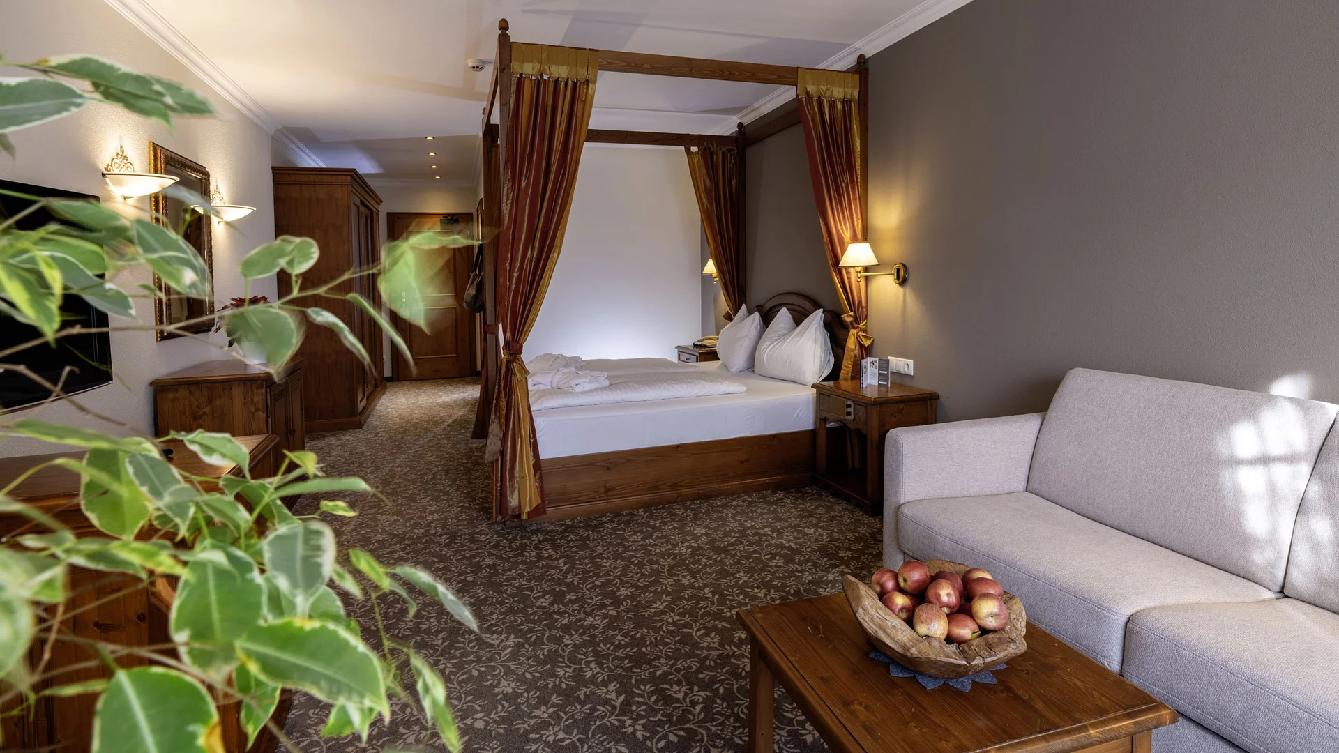 Cozy hotel room with four-poster bed, sofa, and wooden furniture