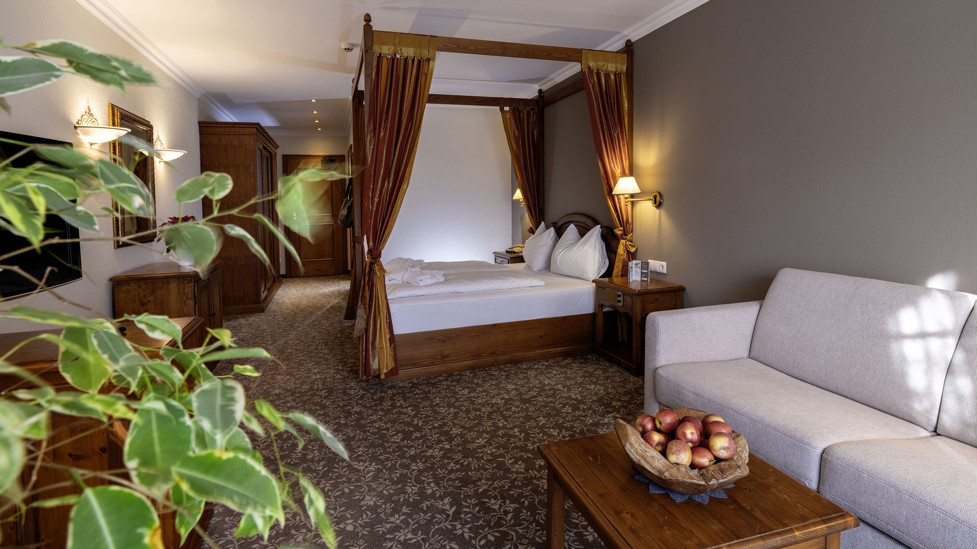 Cozy hotel room with four-poster bed, sofa, and wooden furniture