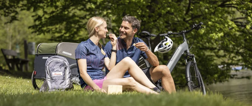 Paar macht Pause beim Fahrradfahren und sitzt auf Gras im Park