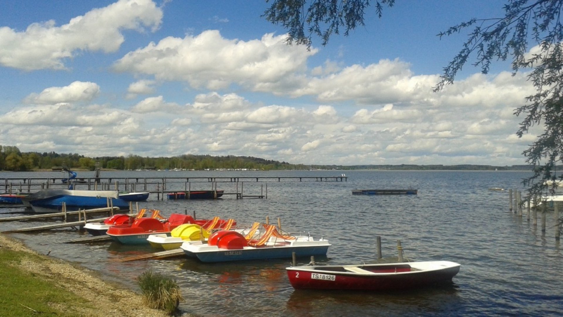 Rowboats and pedal boats by the lakeshore under a cloudy sky