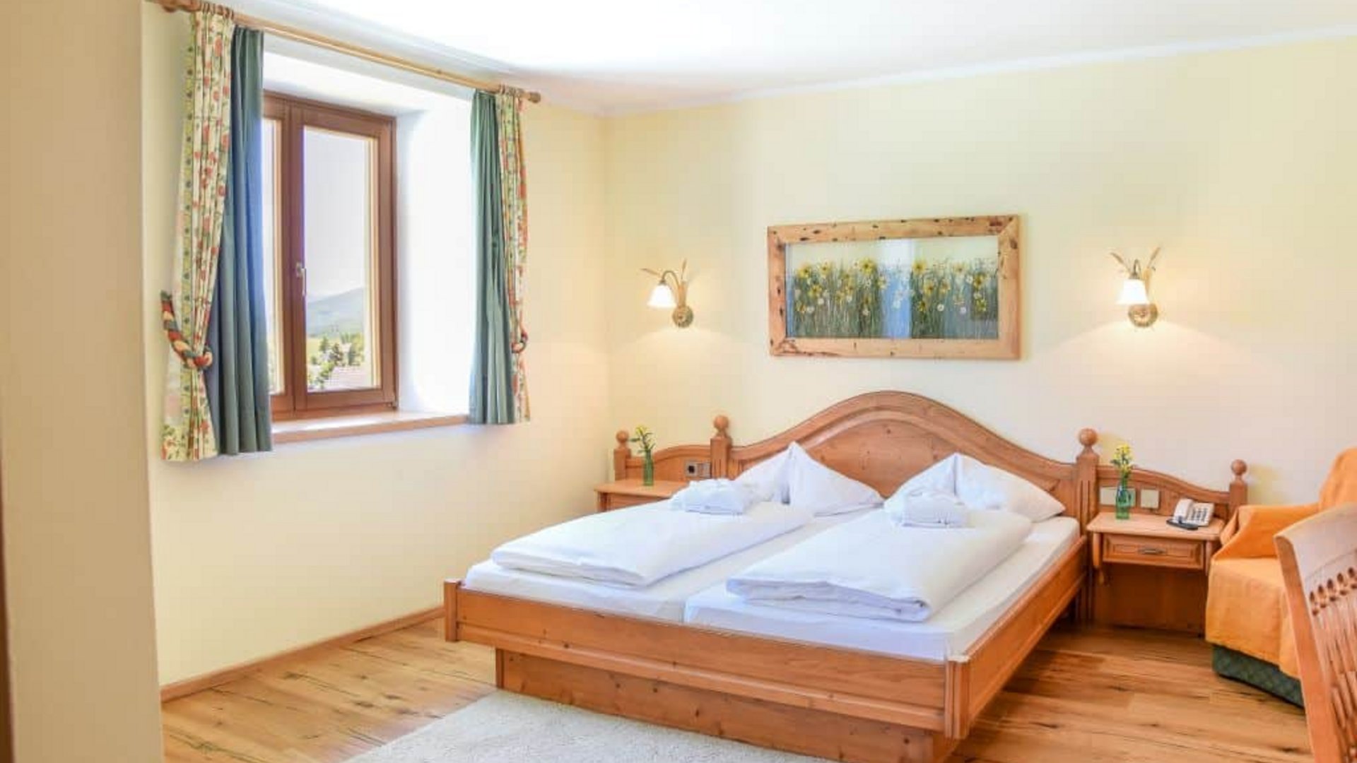 Bright bedroom with double bed, wooden furniture, and window with curtains