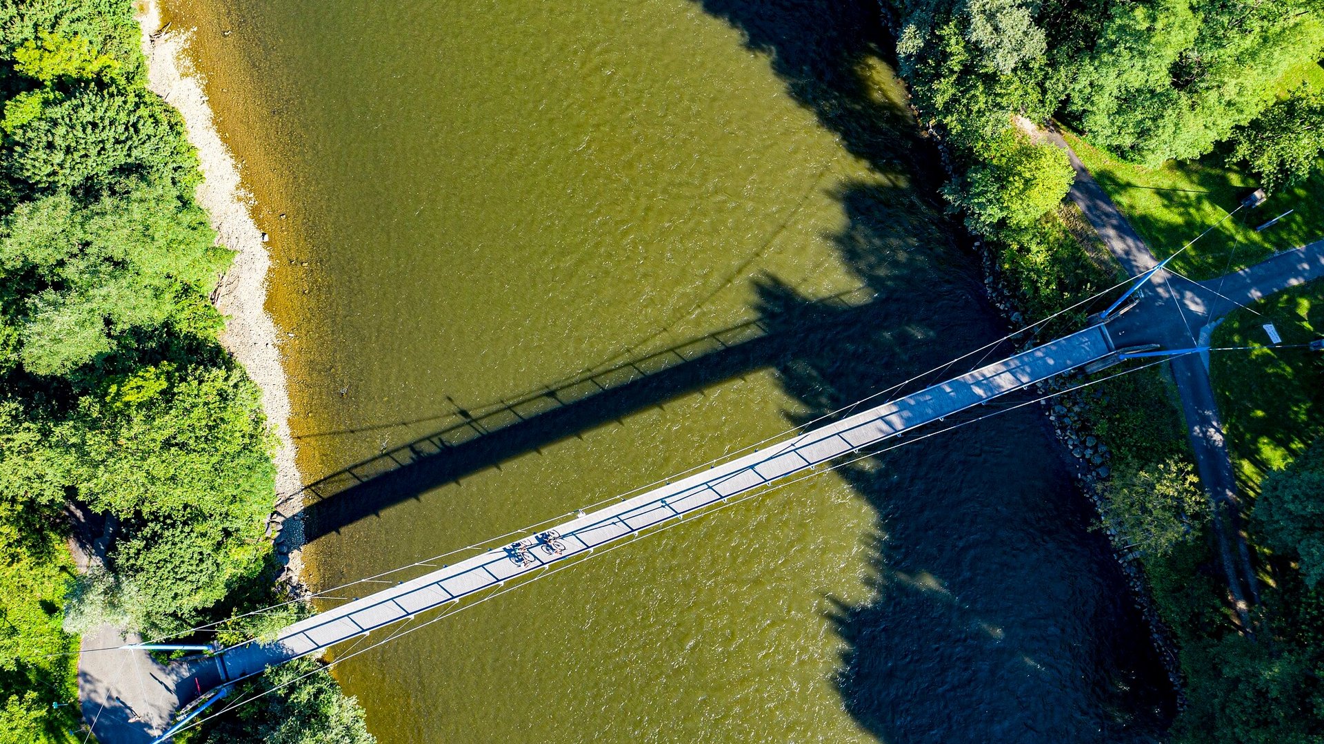 Aerial view of suspension bridge over river with two cyclists