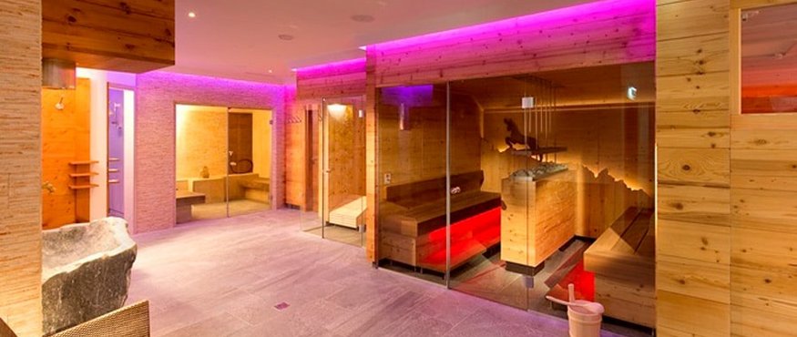 Modern sauna with wooden walls and purple LED lighting