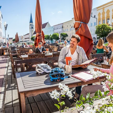 Mensen zitten buiten bij een zonnig café aan de straat