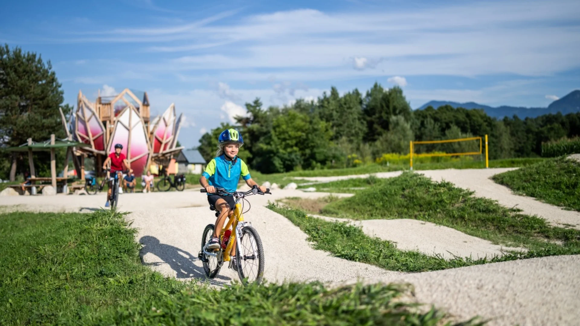 Kinderen fietsen op mountainbikes over een kronkelig onverhard pad op een zonnige dag