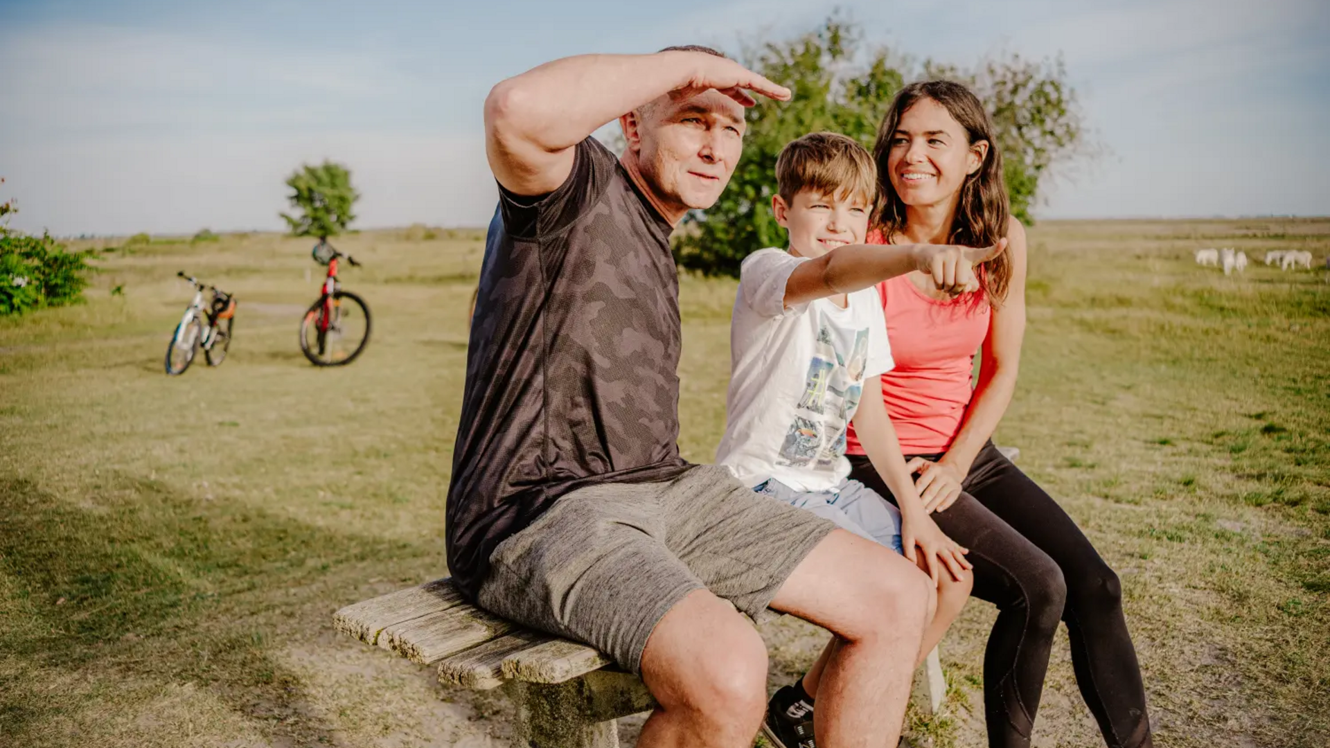 Family sitting on bench in park with bicycles in background