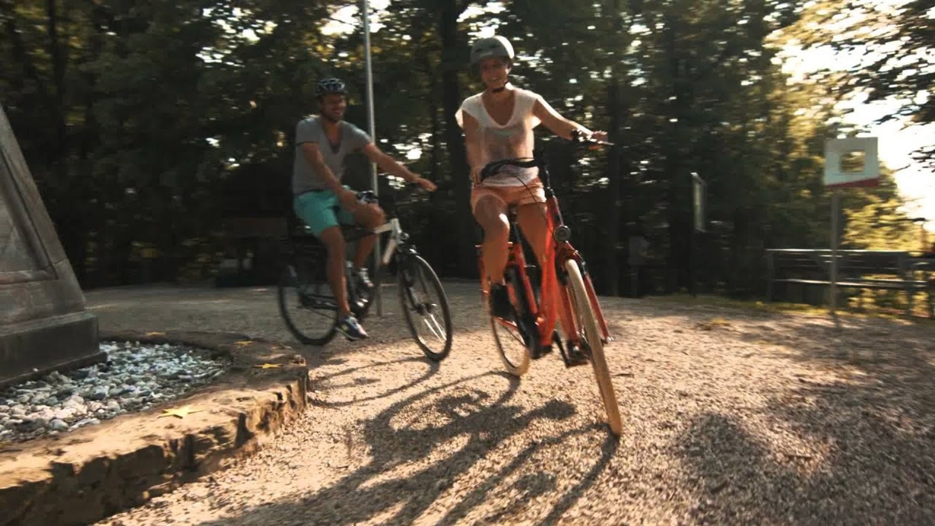 Two people riding bicycles on a sunny forest path