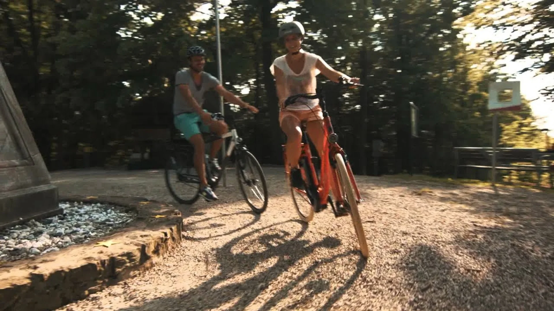 Zwei Personen fahren mit Fahrrädern auf einem sonnigen Waldweg