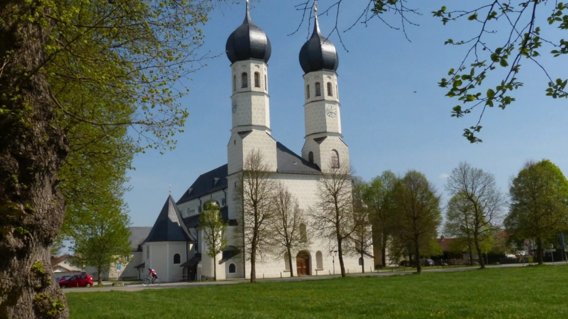Kirche mit Zwiebelkuppeln in einer grünen Parkanlage bei blauem Himmel