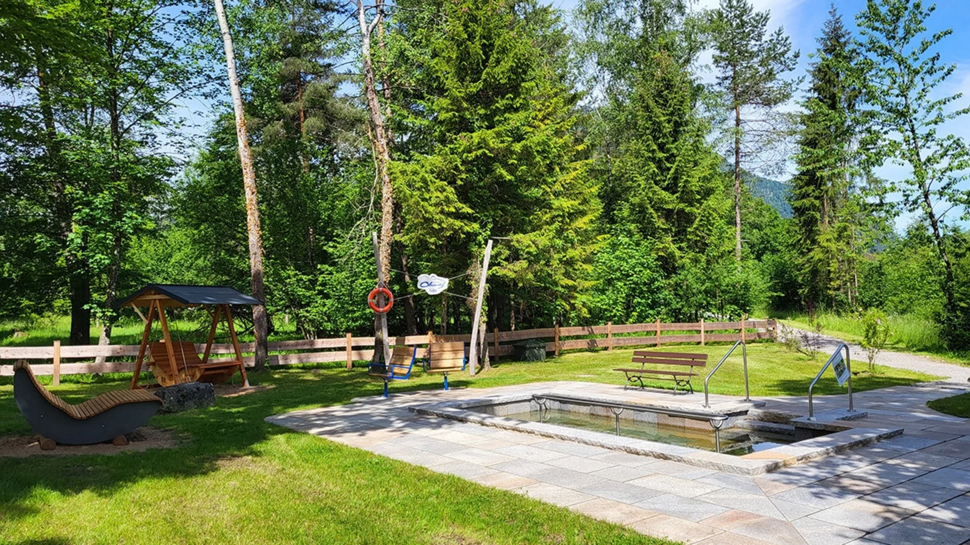 Kleines Außenbecken in einem Park mit Bäumen und Sitzgelegenheiten