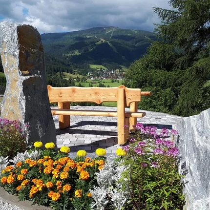 Houten bank met bloemen en bergzicht onder bewolkte lucht