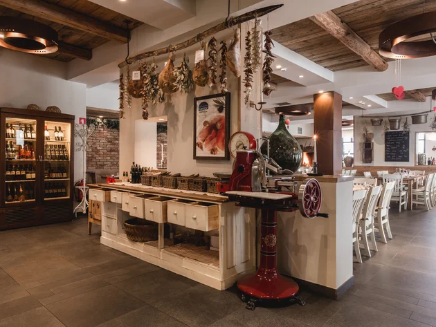 Rustikales Restaurantinterieur mit hängenden getrockneten Kräutern und Weinregal