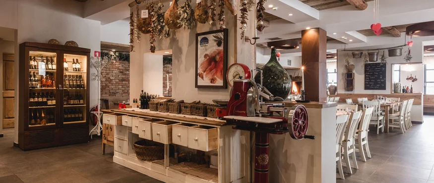 Rustikales Restaurantinterieur mit hängenden getrockneten Kräutern und Weinregal
