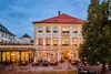 Collective enquiries Evening view of Hotel Zur Post with lit outdoor seating and guests