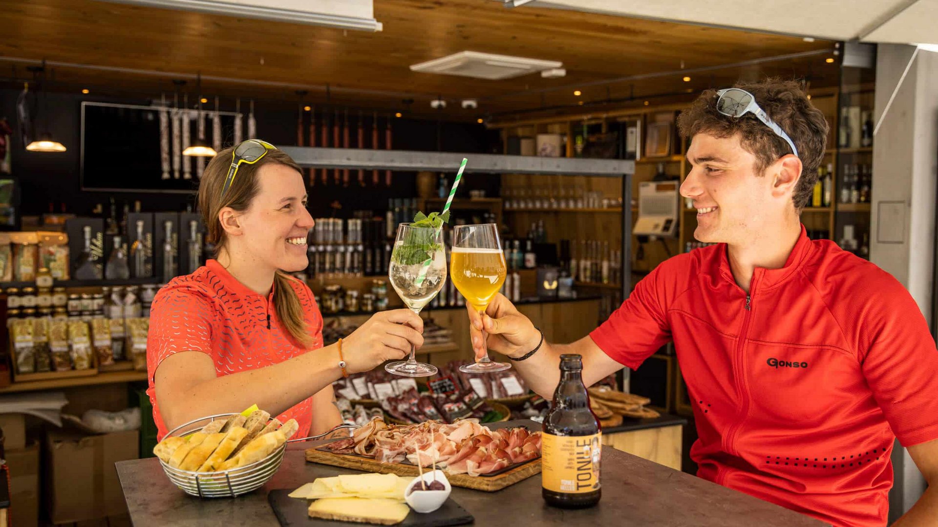 Two people clinking drinks at a cozy restaurant with food on the table