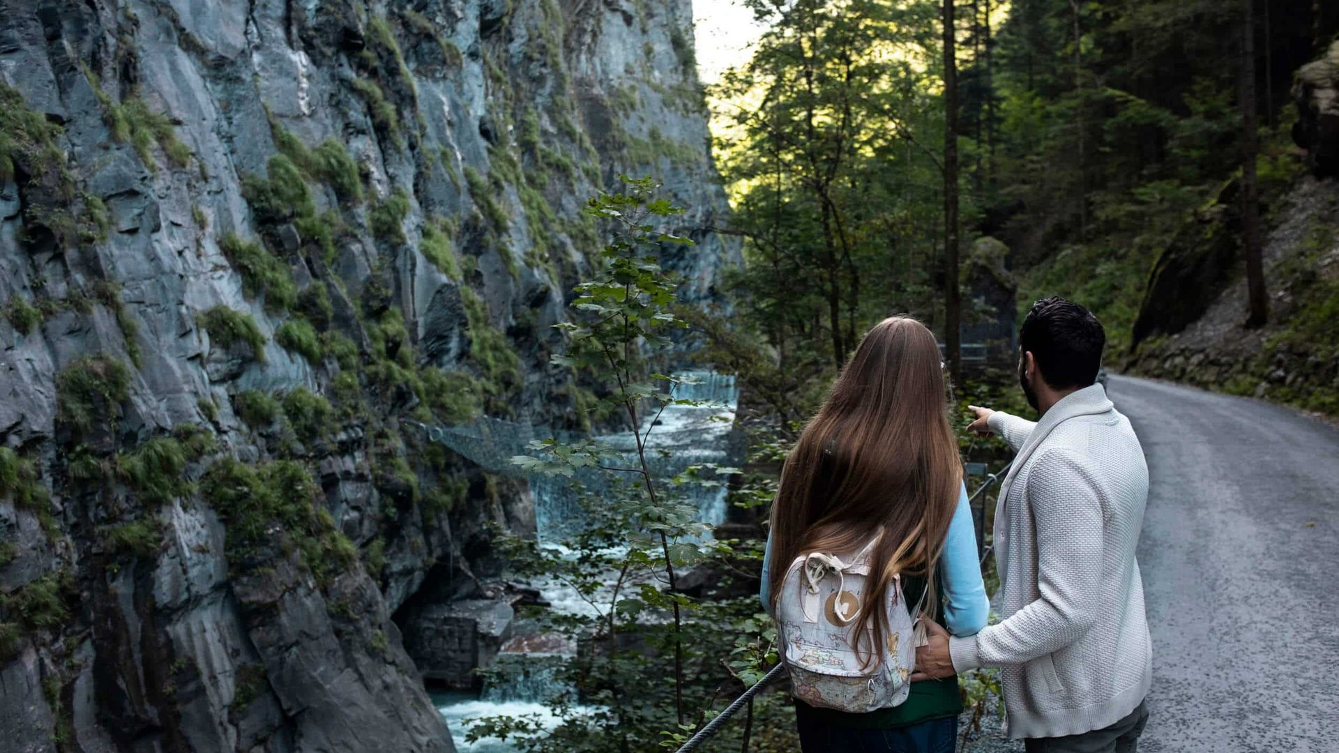 Couple hiking on a path beside a rocky gorge with a river