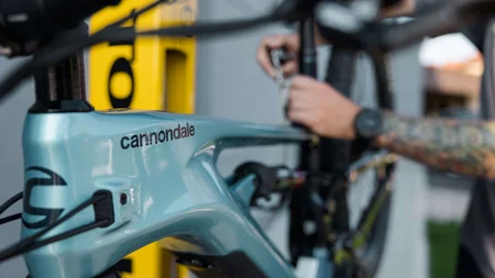 Nahaufnahme eines blauen Cannondale-Fahrradrahmens mit einem tätowierten Arm