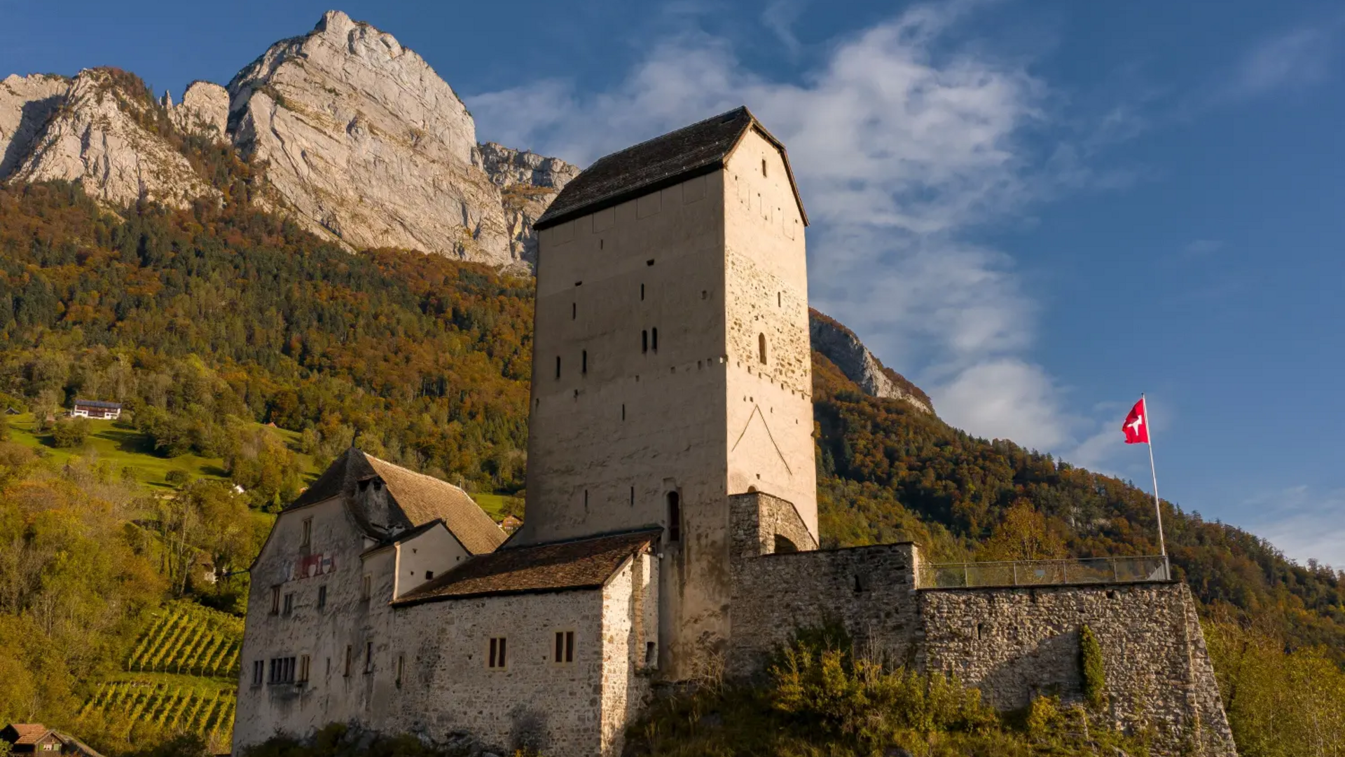 Altes Schloss in den Alpen mit Schweizer Flagge im Herbst