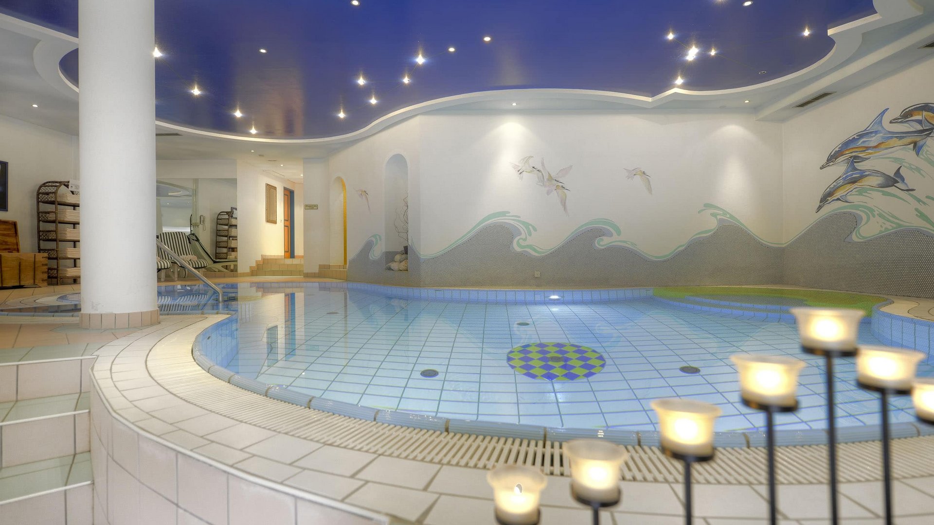 Indoor pool with blue-white tiles and ceiling lights in spa area