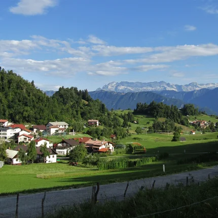 Dorp in groene heuvels met bergen en blauwe lucht op de achtergrond