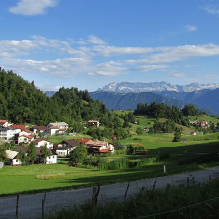 Village in green hills with mountains and blue sky in the background