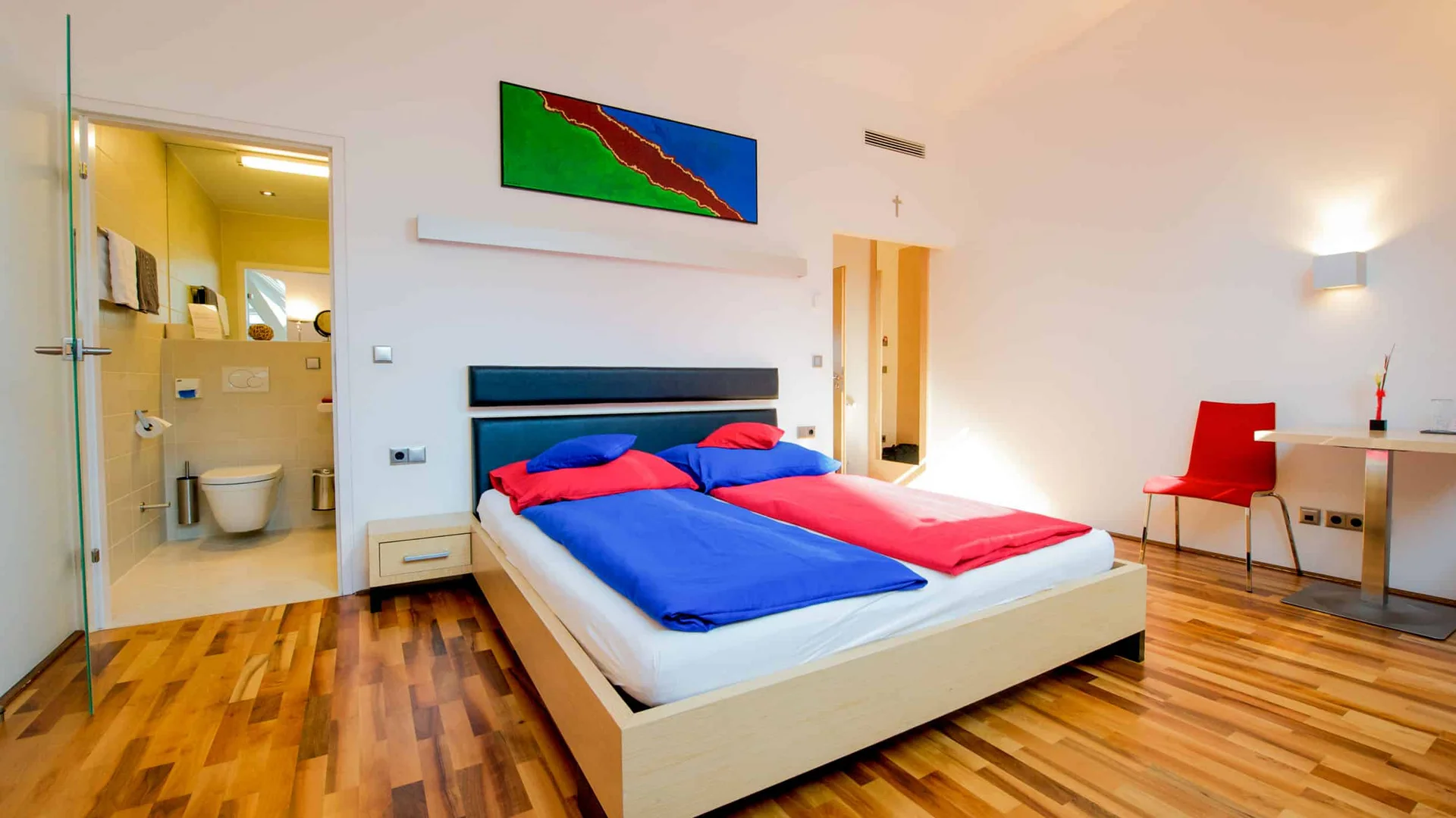 Moderne slaapkamer met tweepersoonsbed en aangrenzende badkamer